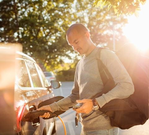 man met tas laadt een elektrische auto op