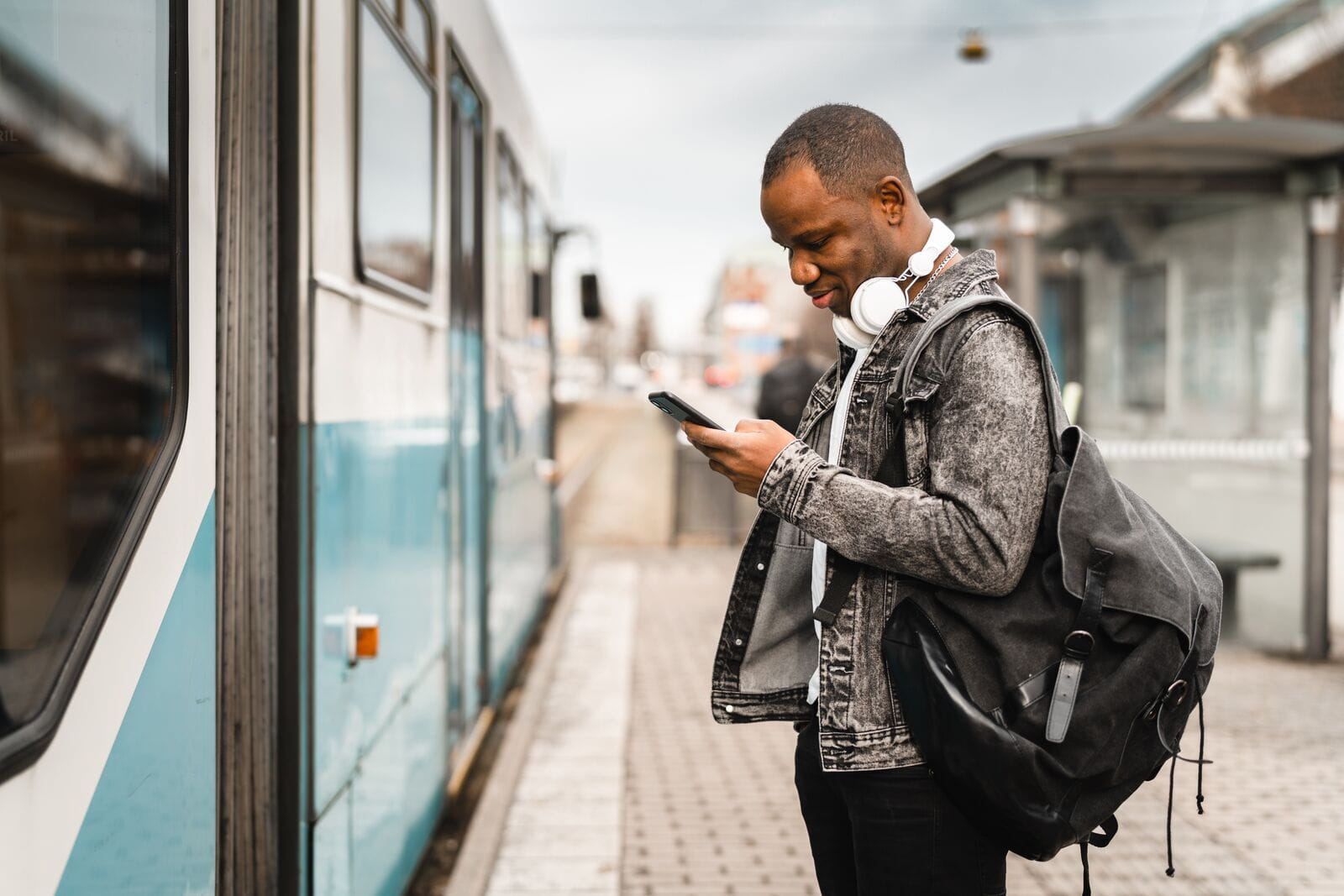 Image d'un homme allant monter dans un train tenant en main son téléphone