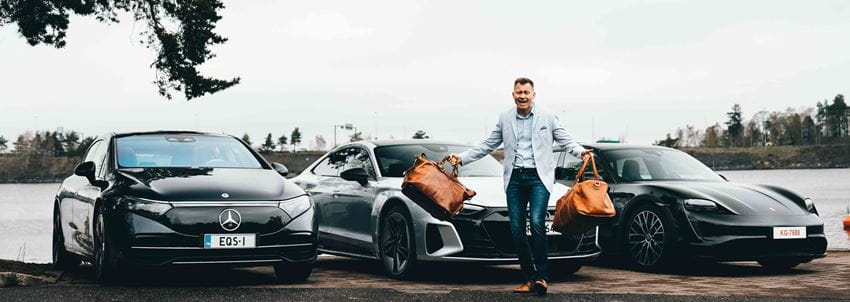 Man carrying bags in front of 3 EVs - winter - Finland